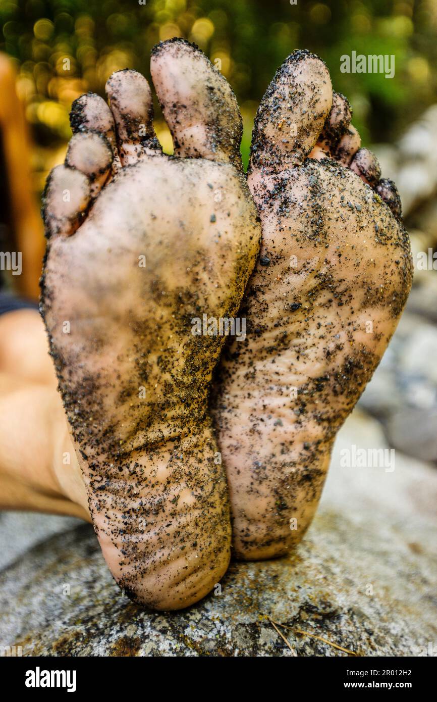 Schmutzige Füße eines Trekkers, der neben dem Cinqueta-Fluss, dem Gistaín-Tal, den Aragonesischen Pyrenäen, Huesca, Spanien ruht. Stockfoto