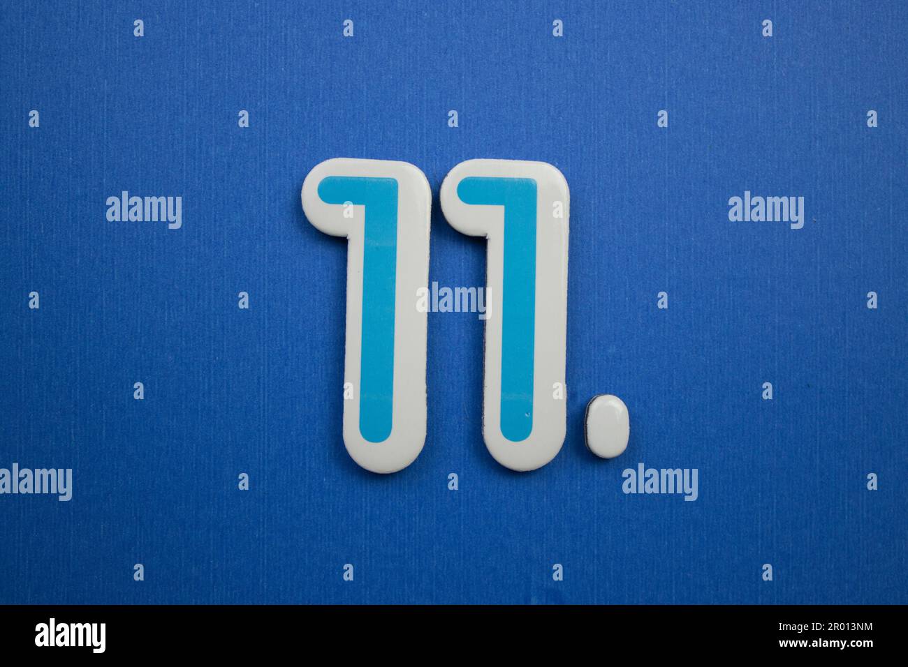 Die Zahl 11 in hellblau und weiß, auf blauem Hintergrund, von oben fotografiert. Stockfoto