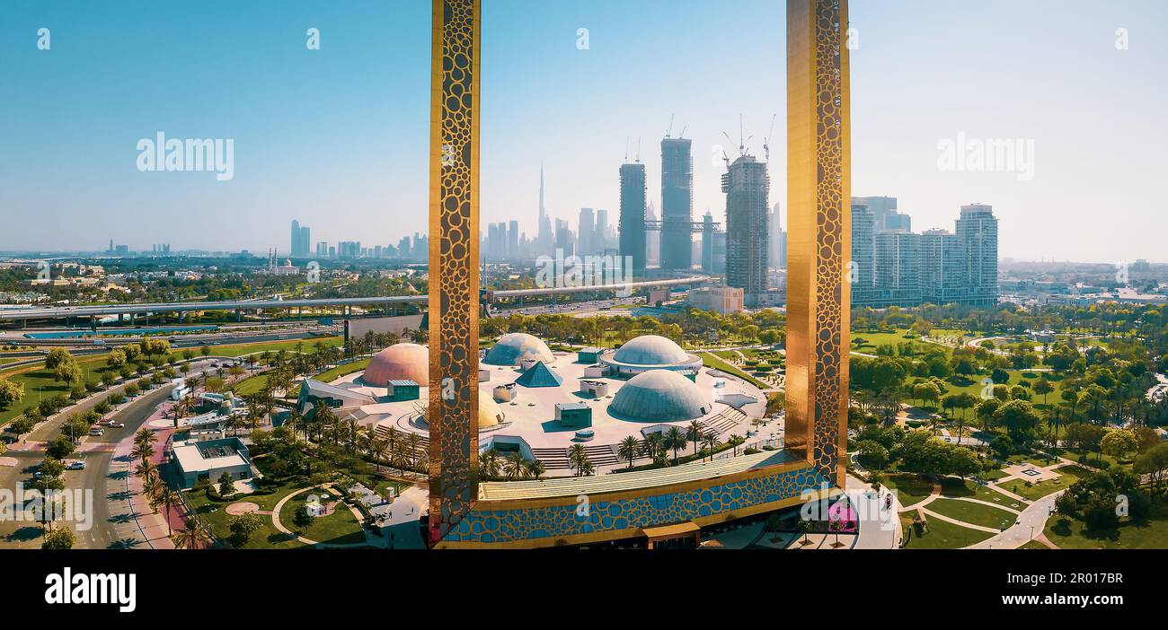 Dubai Skyline durch den großen goldenen Rahmen mit nahe gelegenem Park und Dubai Skyline aus der Vogelperspektive auf das Emirat Stockfoto