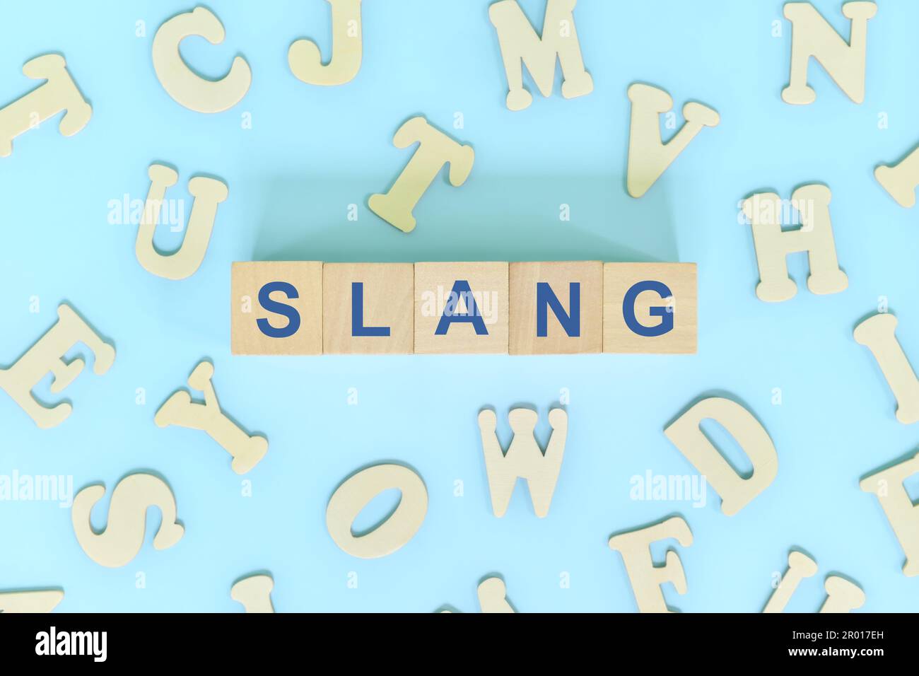 Slang in Sprache und Sprachbegriff. Holzblöcke Typografie Wort flach auf blauem Hintergrund. Stockfoto