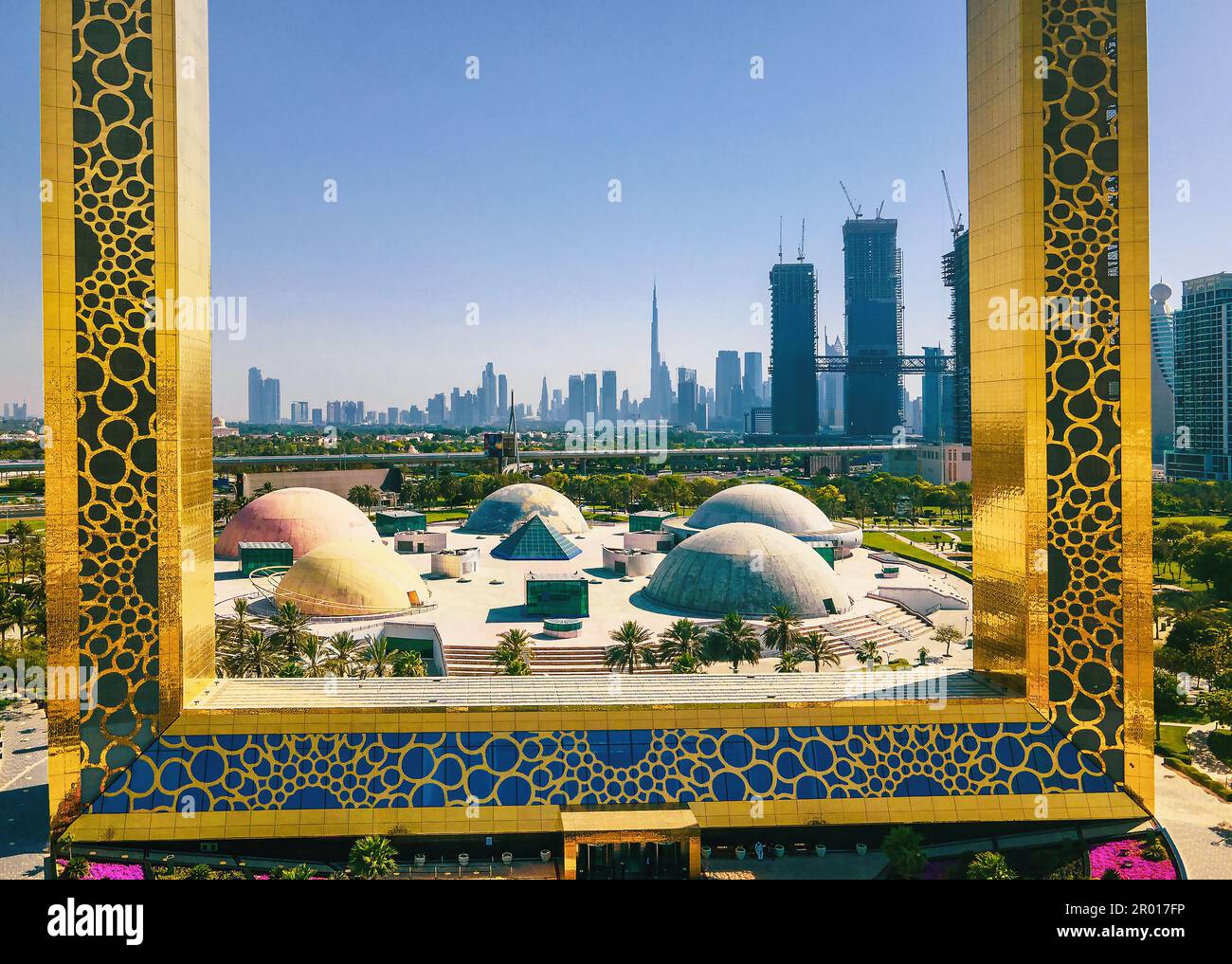 Dubai Skyline durch den großen goldenen Rahmen mit nahe gelegenem Park und Dubai Skyline aus der Vogelperspektive auf das Emirat Stockfoto