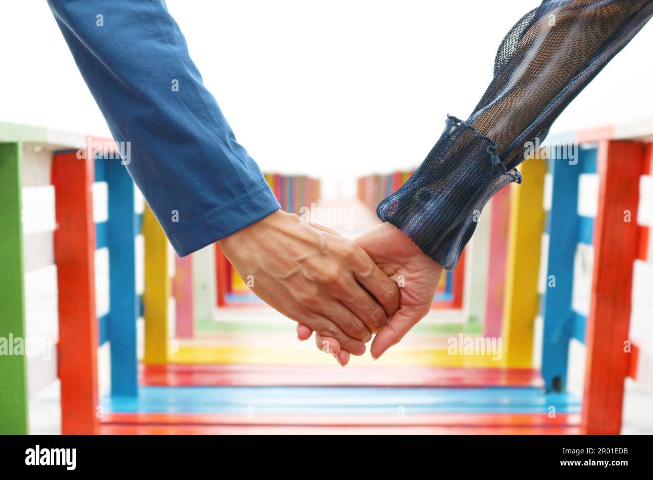 Ein Paar, das Hände auf einer bunten Holzbrücke hält Stockfoto