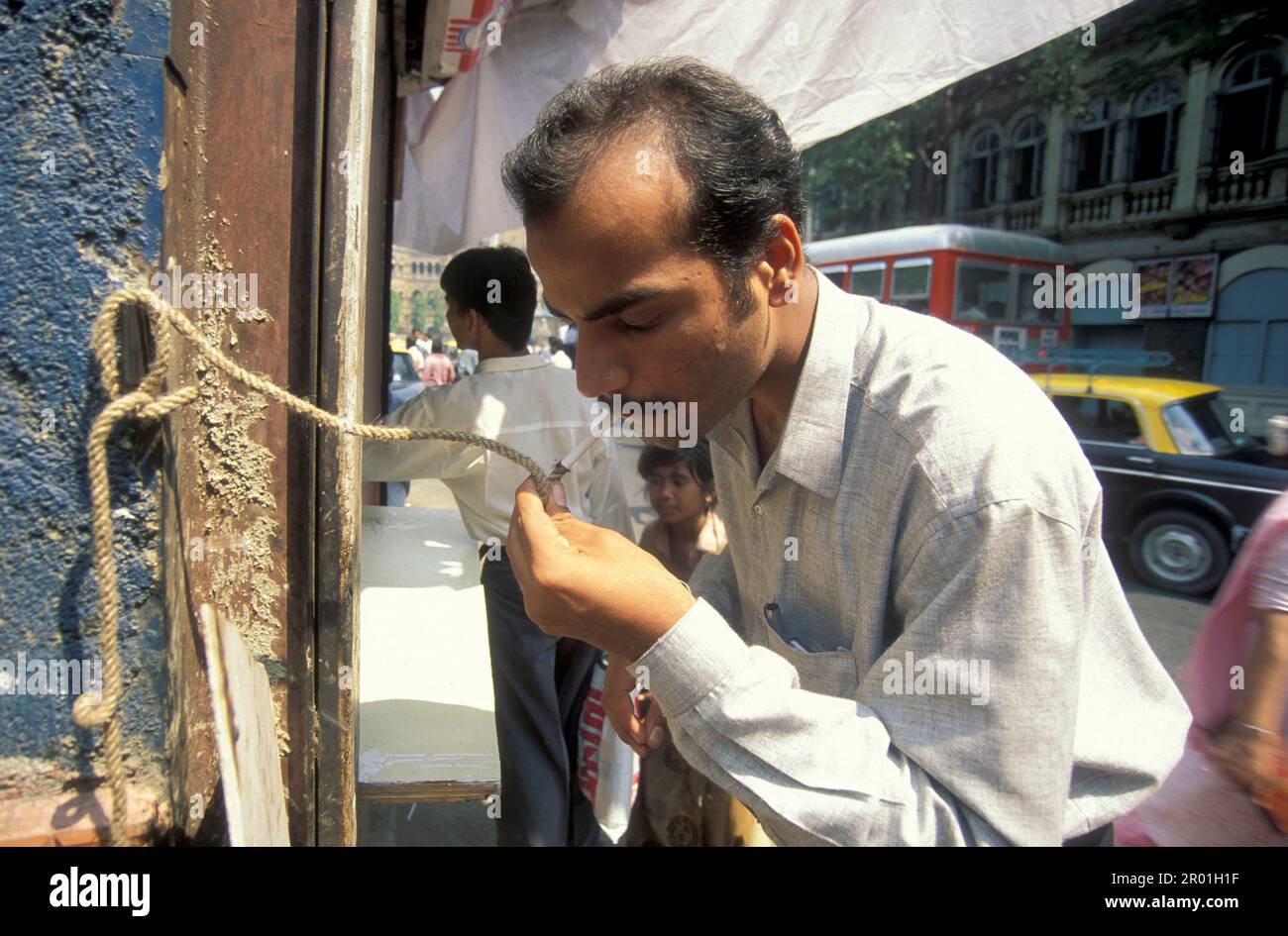 Ein Mann wird für seine Zigaretten auf einer Feuerwache an einer Straße im Stadtzentrum von Mumbai in Indien angegriffen. Indien, Mumbai, März 1998 Stockfoto