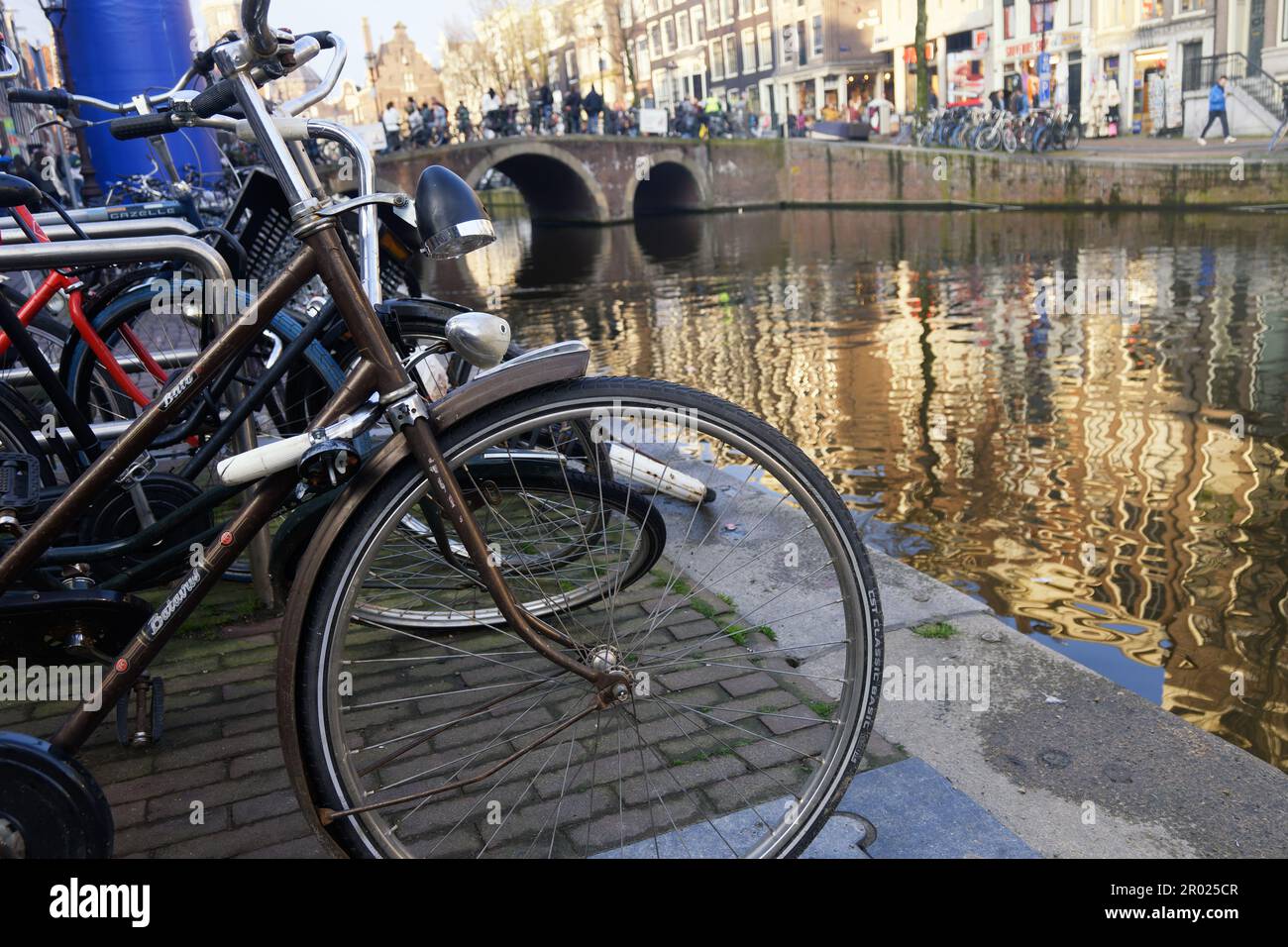 Die traditionelle Art der Erkundung Amsterdams - geparkte Fahrräder. An einem Kanal. Stockfoto