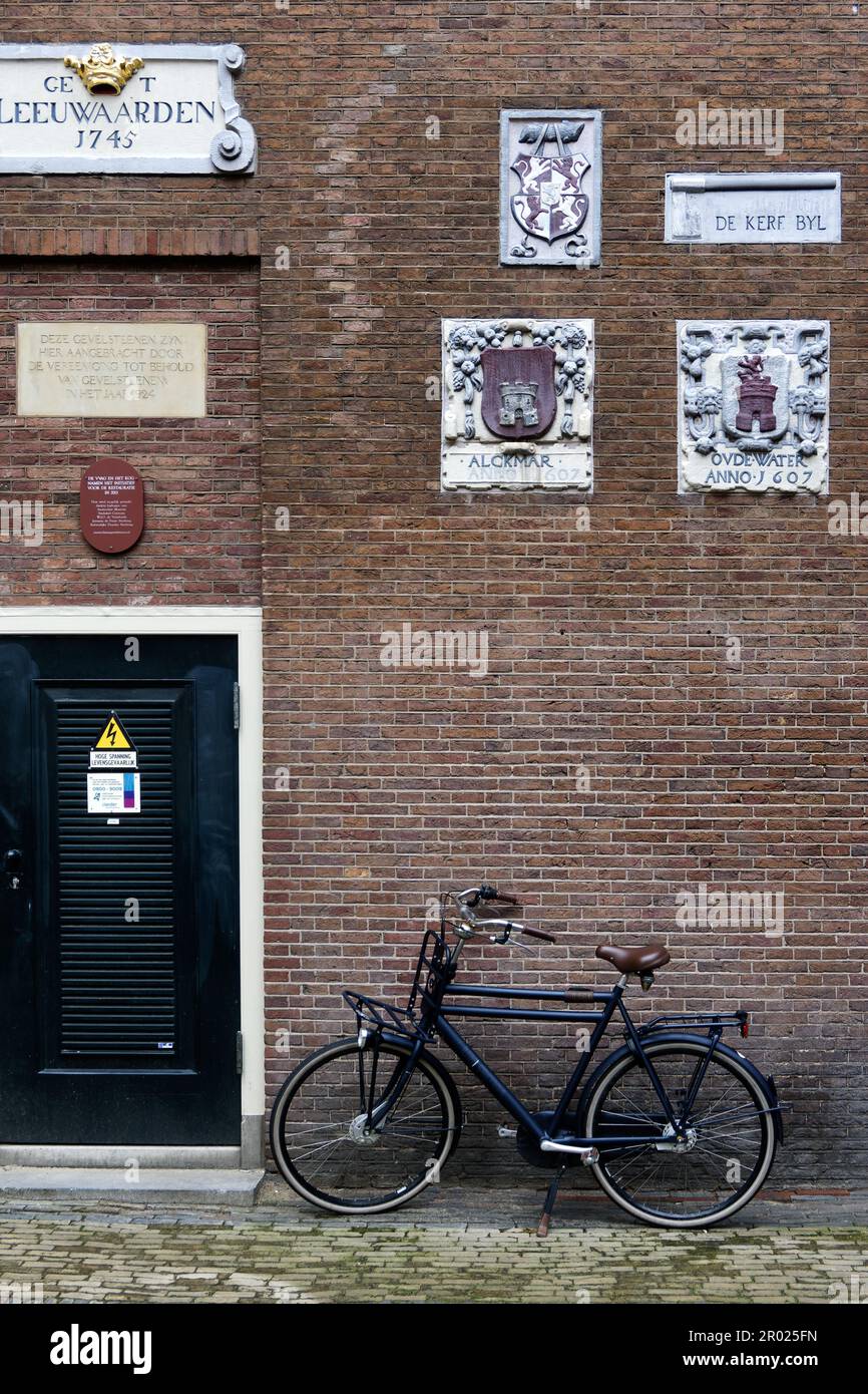 Alte Giebel an einer Wand, die Handwerke und Berufe der Hausbewohner mit Fahrrädern in Amsterdam, Holland, Niederlande, zeigen. Stockfoto