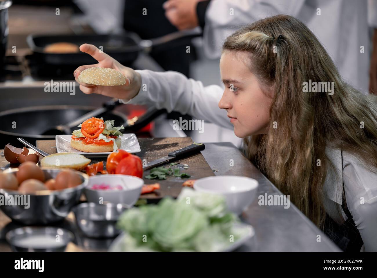 Teenager lernen von erfahrenen Köchen in der Kochschule, um Zutaten zuzubereiten und eine Vielzahl leckerer Mahlzeiten zu kreieren. In einer praktischen Übung wurde die Beziehung zwischen ihnen hergestellt Stockfoto