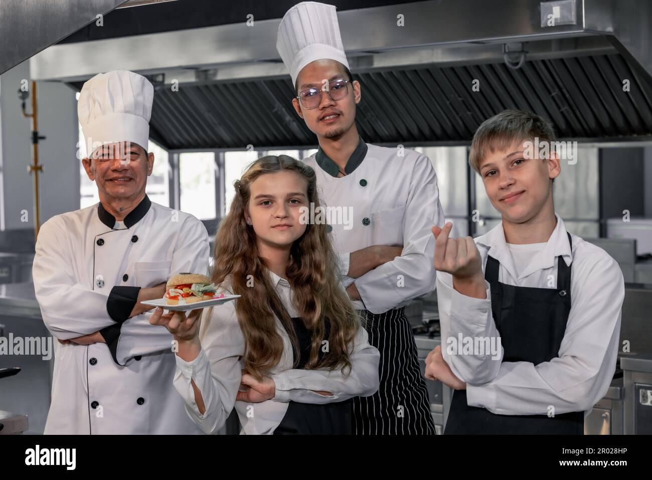 Teenager lernen von erfahrenen Köchen in der Kochschule, um Zutaten zuzubereiten und eine Vielzahl leckerer Mahlzeiten zu kreieren. In einer praktischen Übung wurde die Beziehung zwischen ihnen hergestellt Stockfoto