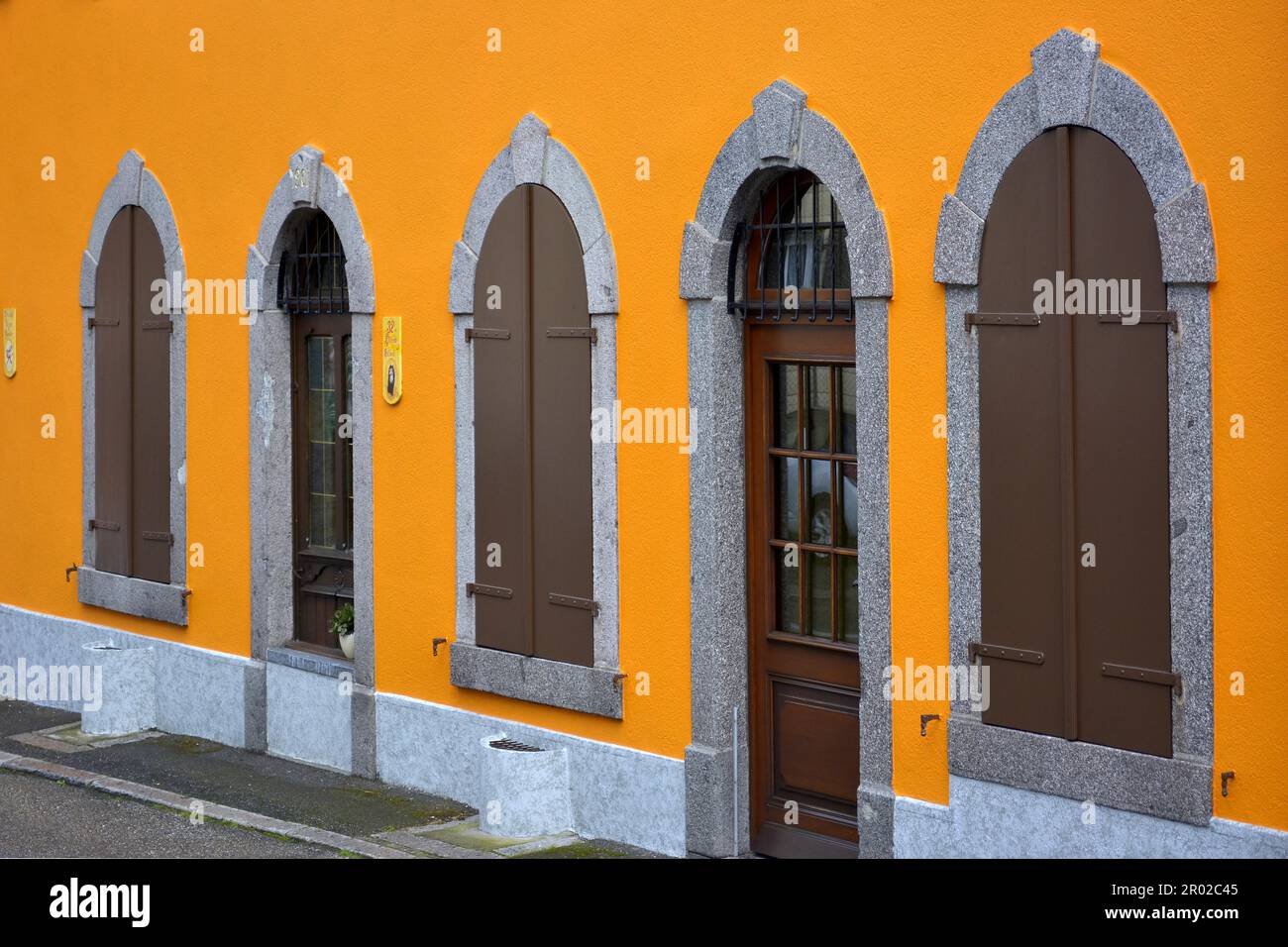 Frankreich, Elsass, Lapoutroie, Stadtzentrum, Altstadt, Rundbogenfenster mit Fensterläden und Tür, orangefarbene Hausfassade Stockfoto