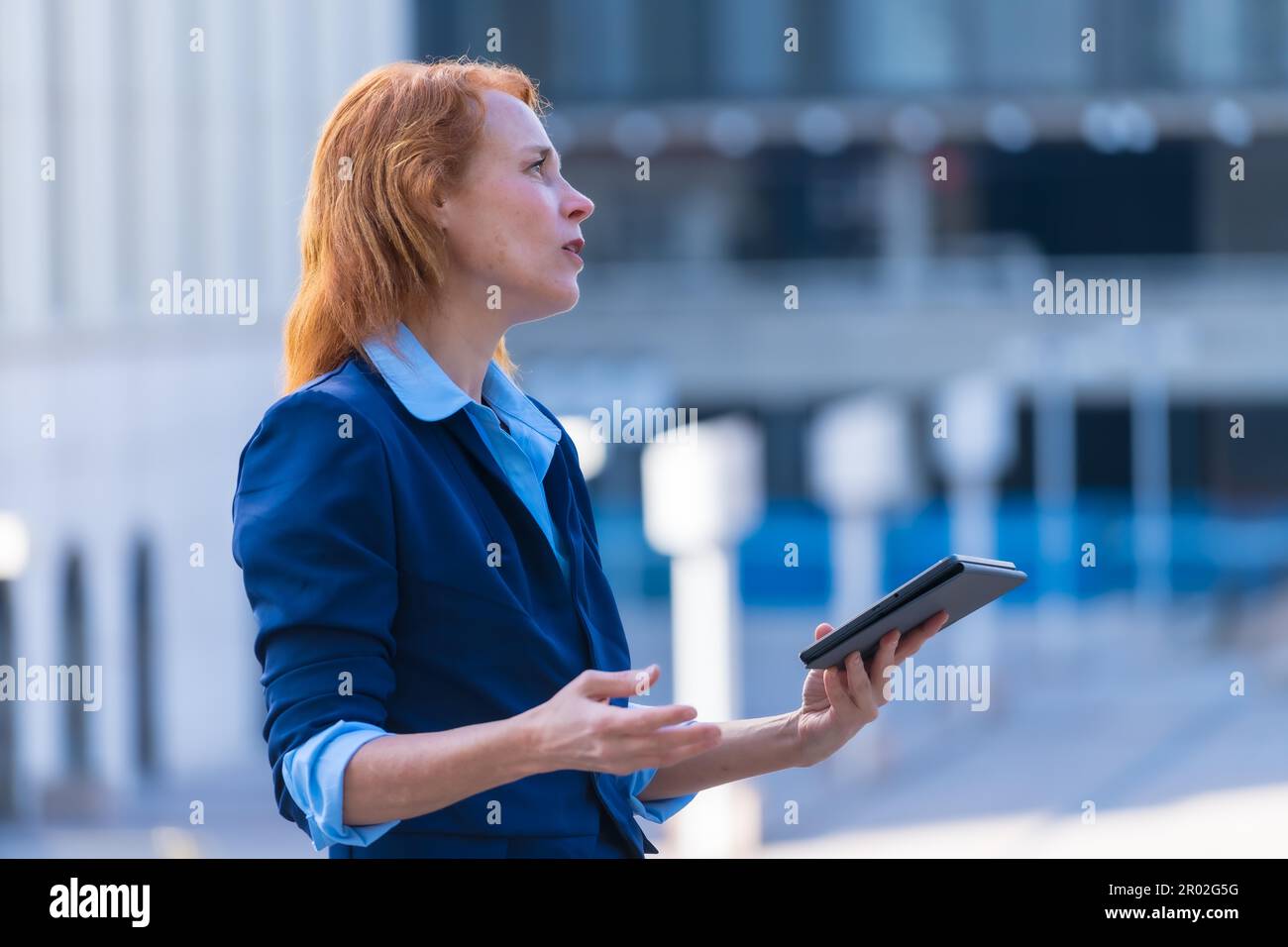 Innovative und technisch versierte rothaarige Geschäftsfrau, die während eines Remote Business mit Kollegen über ein digitales Tablet zusammenarbeitet Stockfoto