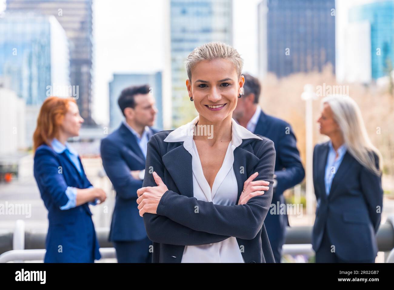 Selbstbewusste weibliche Führungskraft mit Business-Team in moderner Stadtlandschaft Stockfoto