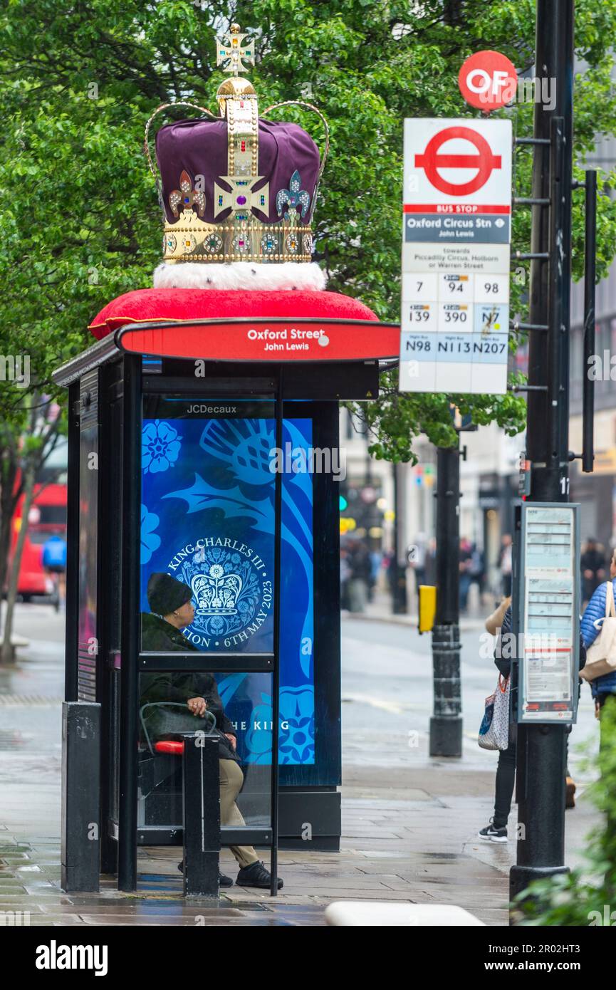 London, Großbritannien. 6. Mai 2023 Eine große Krone schmückt das Dach einer Bushaltestelle in der Nähe des Flagship John Lewis Kaufhauses in der Oxford Street am Tag der Krönung von König Karl III. Und Königin Camilla, während eine digitale Nachricht auf einem Bildschirm an der Bushaltestelle angezeigt wird. Dies ist die erste Krönung des Vereinigten Königreichs seit 70 Jahren und die erste im digitalen Zeitalter. Kredit: Stephen Chung / Alamy Live News Stockfoto