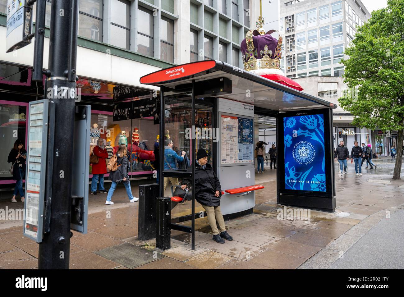 London, Großbritannien. 6. Mai 2023 Eine große Krone schmückt das Dach einer Bushaltestelle in der Nähe des Flagship John Lewis Kaufhauses in der Oxford Street am Tag der Krönung von König Karl III. Und Königin Camilla, während eine digitale Nachricht auf einem Bildschirm an der Bushaltestelle angezeigt wird. Dies ist die erste Krönung des Vereinigten Königreichs seit 70 Jahren und die erste im digitalen Zeitalter. Kredit: Stephen Chung / Alamy Live News Stockfoto