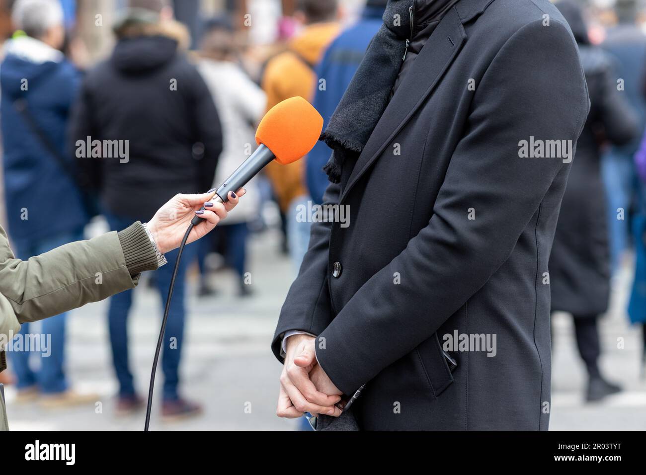 Reporter mit Mikrofon, der ein Medieninterview mit männlichen Politikern oder Geschäftsleuten führt. Straßeninterview oder Vox popoli-Konzept. Stockfoto