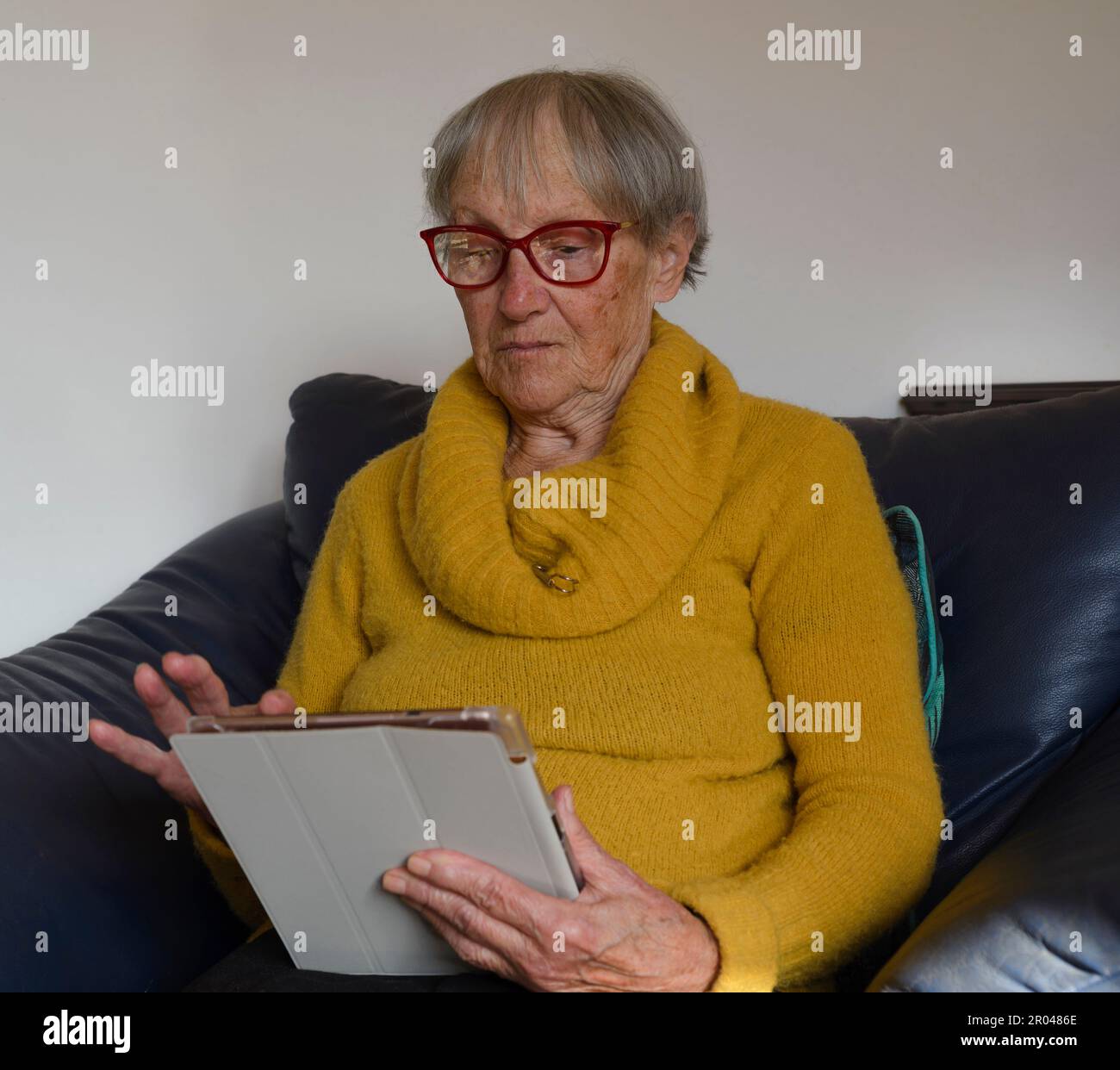 Alte, reife Seniorin, die ein digitales Tablet benutzt und auf den Computer schaut. Virtuelle Anrufe, Online-Meetings, Fernsehen, E-Books lesen, Zeit mit Tec verbringen Stockfoto