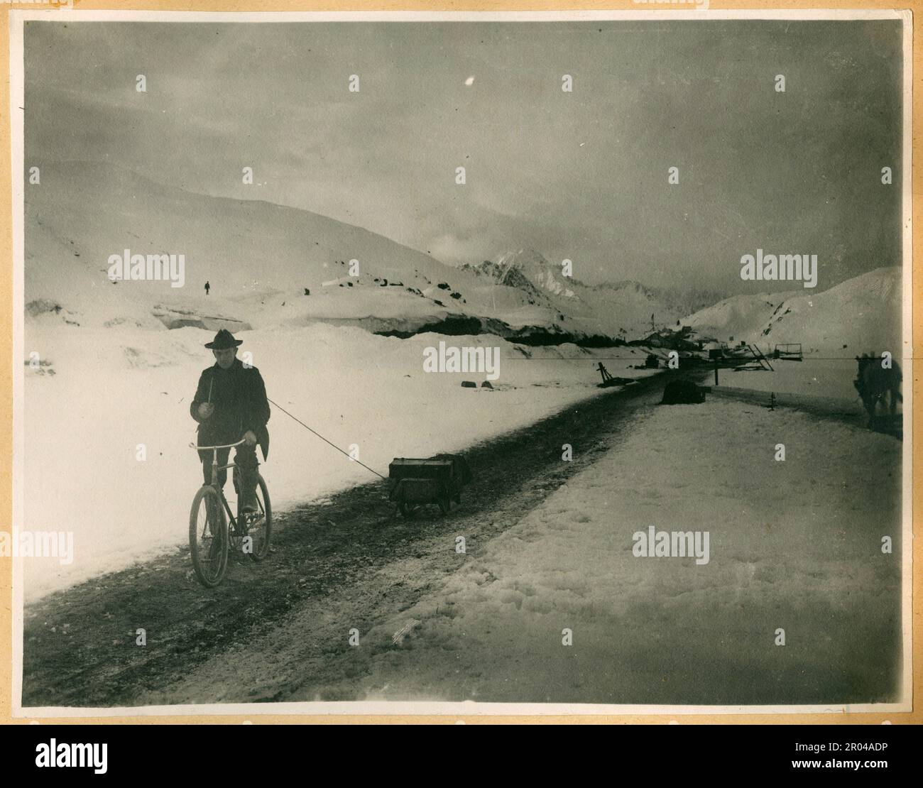 Ein Mann auf einem Fahrrad, der einen Schlitten am Gipfel des White Pass Trails, Ca. 1899. Der White Pass war eine der wichtigsten Routen der Goldsucher, die von Skagway zu den Goldfeldern des Yukon reisten. Stockfoto