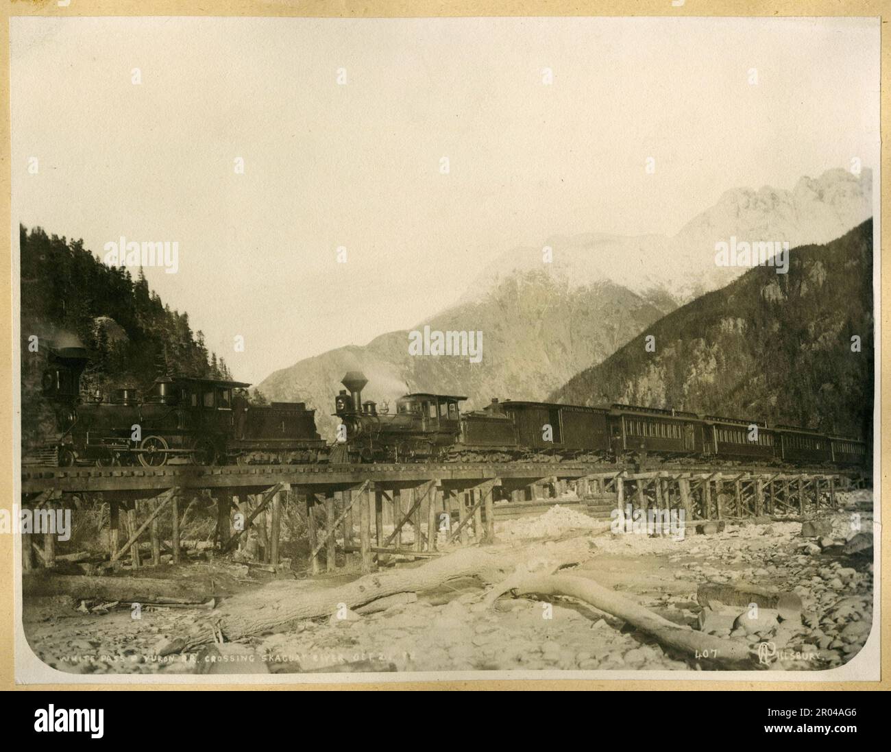 White Pass und Yukon Railway, die den Skagway River überqueren, 21. Oktober 1898. Während des Klondike-Goldrauschs war der White Pass eine der Routen, die von Goldsuchern genutzt wurden, um von Skagway zu den Yukon-Goldfeldern zu reisen. Im April 1898 wurde die White Pass and Yukon Railroad Company gegründet, um einen einfacheren Weg durch den Pass zu finden. Die Bauarbeiten an der Eisenbahn begannen im folgenden Monat. Tausende von Arbeitern arbeiteten rund um die Uhr unter betrügerischen Bedingungen, um das Projekt abzuschließen. Die Eisenbahnstrecke wurde am White Pass am 20. Februar 1899 fertiggestellt und erreichte Lake Bennett am 6. Juli 1899. Stockfoto