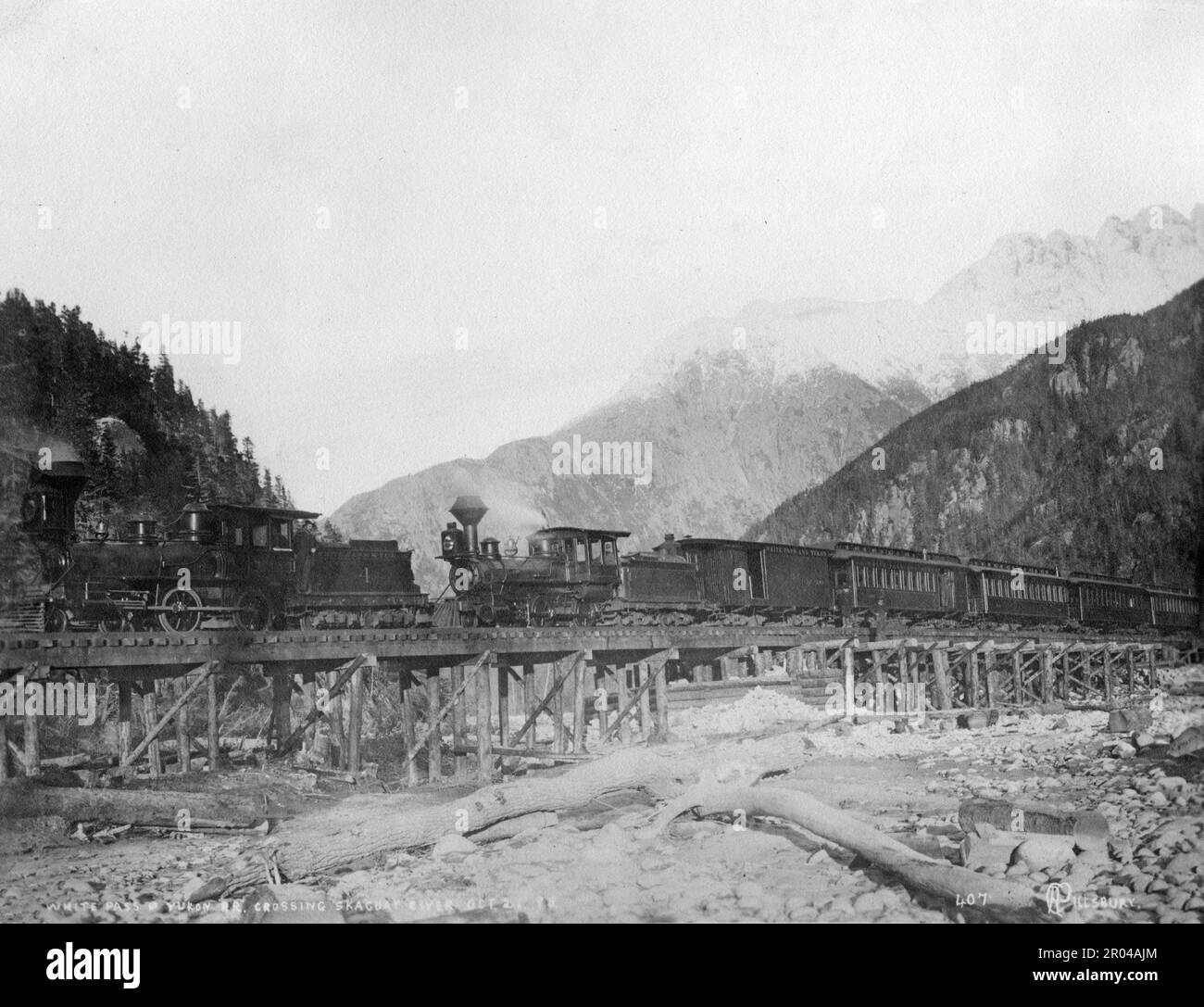 White Pass und Yukon Railway, die den Skagway River überqueren, 21. Oktober 1898. Während des Klondike-Goldrauschs war der White Pass eine der Routen, die von Goldsuchern genutzt wurden, um von Skagway zu den Yukon-Goldfeldern zu reisen. Im April 1898 wurde die White Pass and Yukon Railroad Company gegründet, um einen einfacheren Weg durch den Pass zu finden. Die Bauarbeiten an der Eisenbahn begannen im folgenden Monat. Tausende von Arbeitern arbeiteten rund um die Uhr unter betrügerischen Bedingungen, um das Projekt abzuschließen. Die Eisenbahnstrecke wurde am White Pass am 20. Februar 1899 fertiggestellt und erreichte Lake Bennett am 6. Juli 1899. Stockfoto