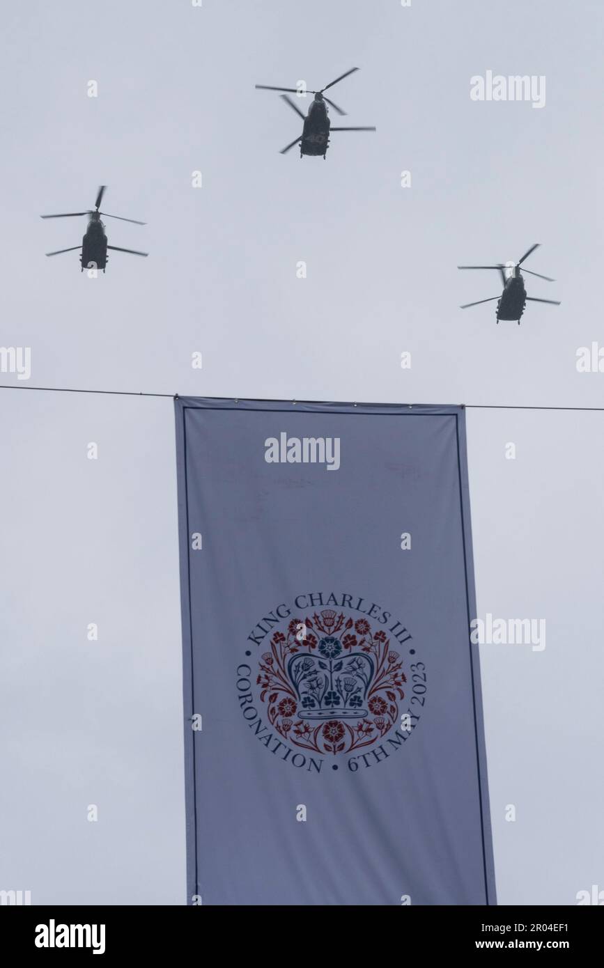 RAF Chinook Helikopter in der Fahne zur Krönung von König Karl III. Fliegen über ein Banner mit Ereignis und Datum Stockfoto