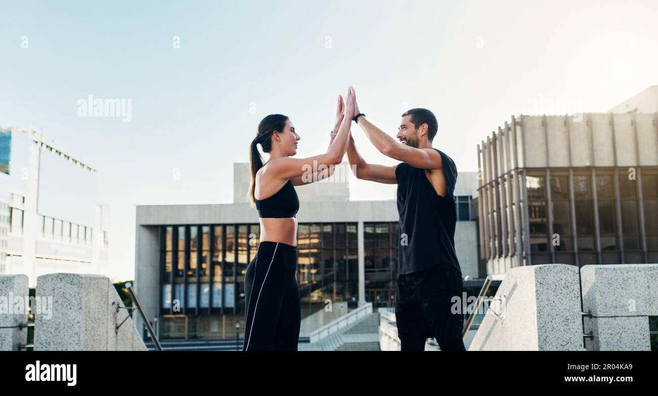 Niemand hält dich so motiviert wie ein Trainingspartner. Ein junges Paar, das sich während des Trainings in der Stadt gegenseitig einen High Five gibt. Stockfoto