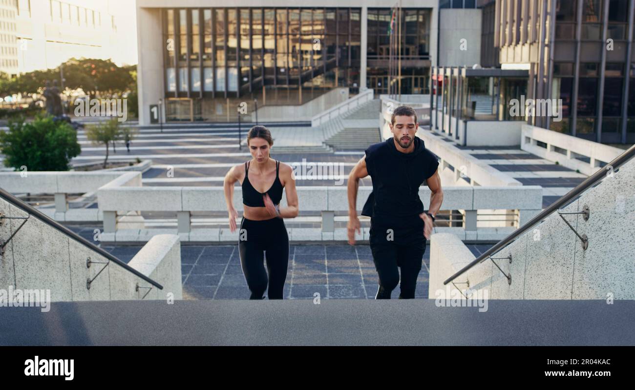 Nichts tötet Fettzellen besser als Kardio. Ein junger Mann und eine junge Frau, die zusammen die Treppen in der Stadt hochlaufen. Stockfoto