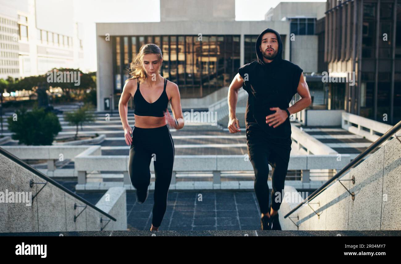 Immer in Bewegung bleiben, immer besser werden. Ein junger Mann und eine junge Frau, die zusammen die Treppen in der Stadt hochlaufen. Stockfoto