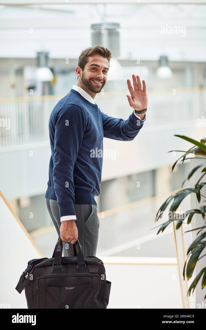 Bis zum nächsten großen Erfolg. Porträt eines jungen Geschäftsmannes, der winkt, während er eine Tasche trägt. Stockfoto