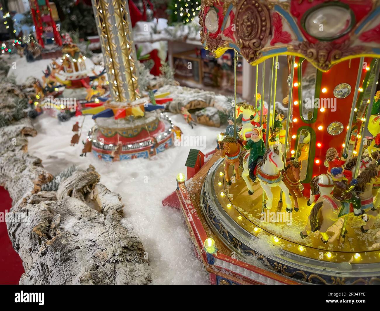 Weihnachtsszene einer Weihnachtsmesse mit einem Karussell mit Figuren im Vordergrund, Nachbildung einer Weihnachtsmesse mit Modellen in Keramikmaßstab Stockfoto