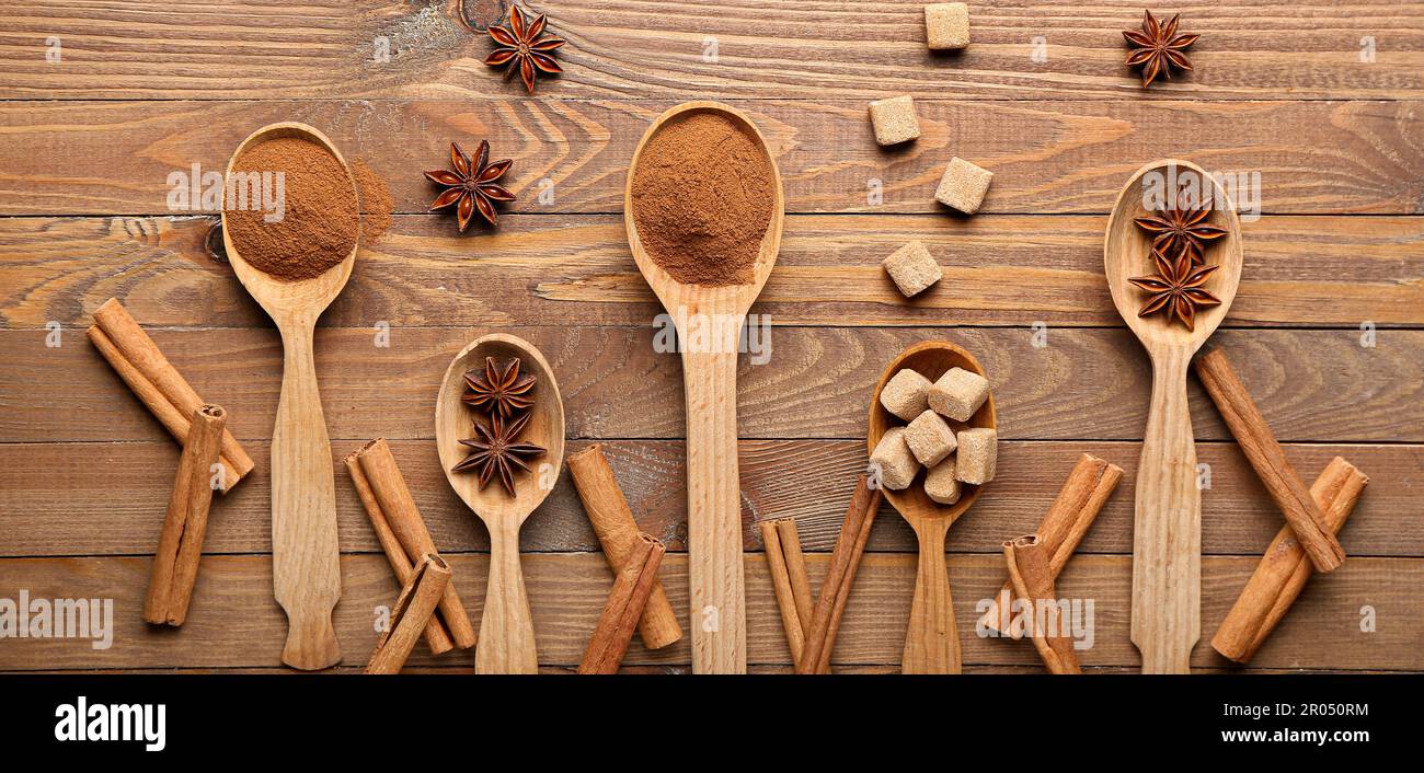 Löffel mit Zimt, Anis und Zucker auf Holzhintergrund, Draufsicht Stockfoto