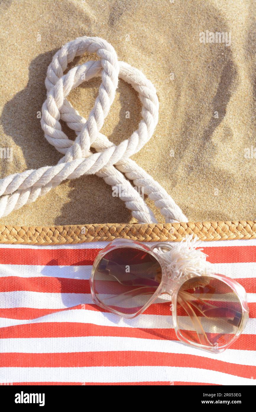 Stilvolle Sonnenbrille und Strandtasche auf Sand Stockfoto