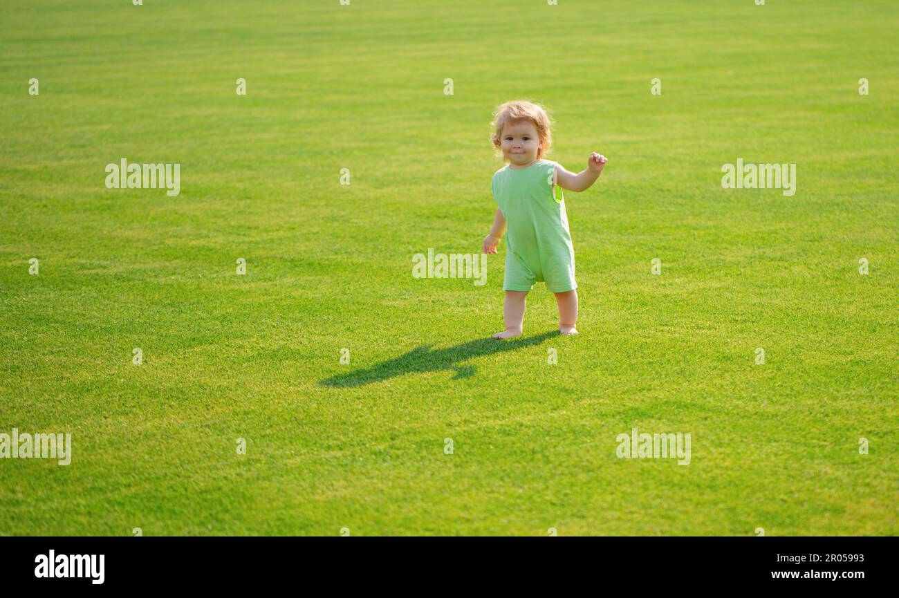 Nette lustige Baby Junge lernen, Schritt zu kriechen, Spaß beim Spielen auf dem Rasen im Garten. Stockfoto