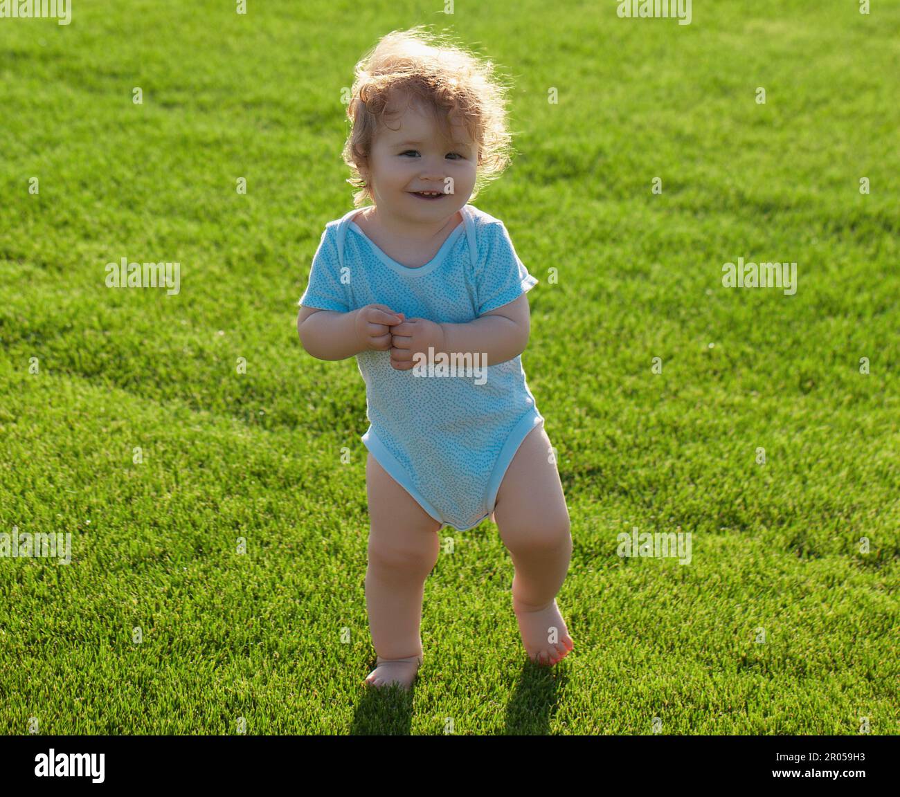 Fröhliches Baby im Gras auf dem Fieald am Sommerabend. Lächelndes Kind im Freien. Stockfoto