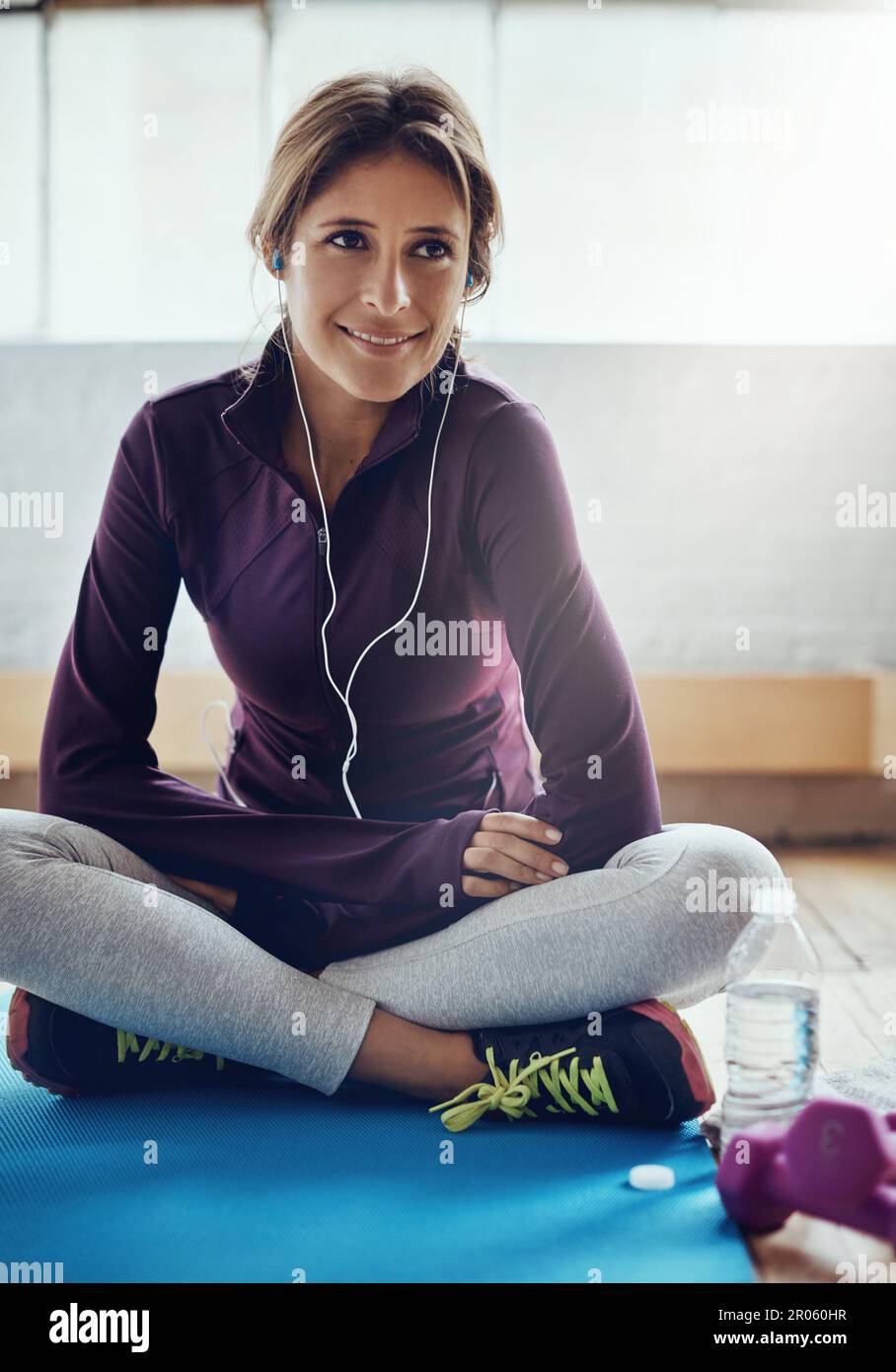 Das ist der perfekte Soundtrack, um mich in Form zu bringen. Eine attraktive junge Frau, die Musik hört, während sie zu Hause trainiert. Stockfoto