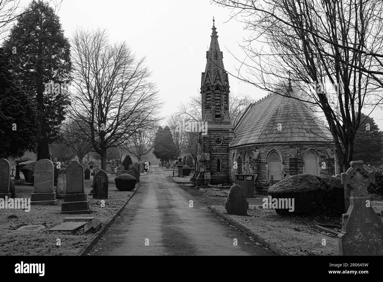 Graustufenbild eines Friedhofs mit einer historischen Kirche im Hintergrund Stockfoto