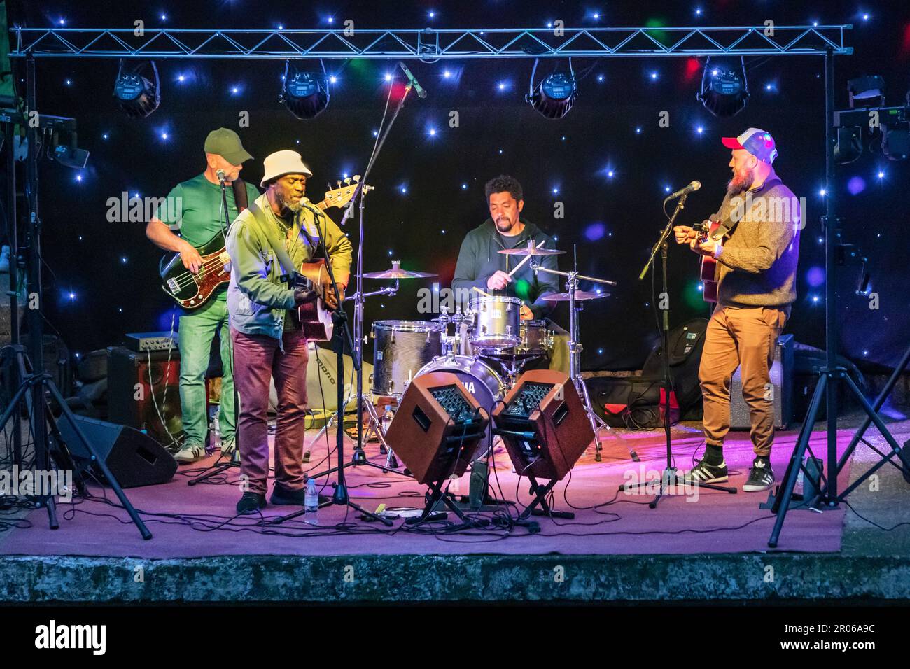 Gummistiefel veranstalten eine Reggae-Aufführung auf der Kanalseite in Hythe, Kent, um die Krönung von König Karl dem Dritten zu feiern. Stockfoto