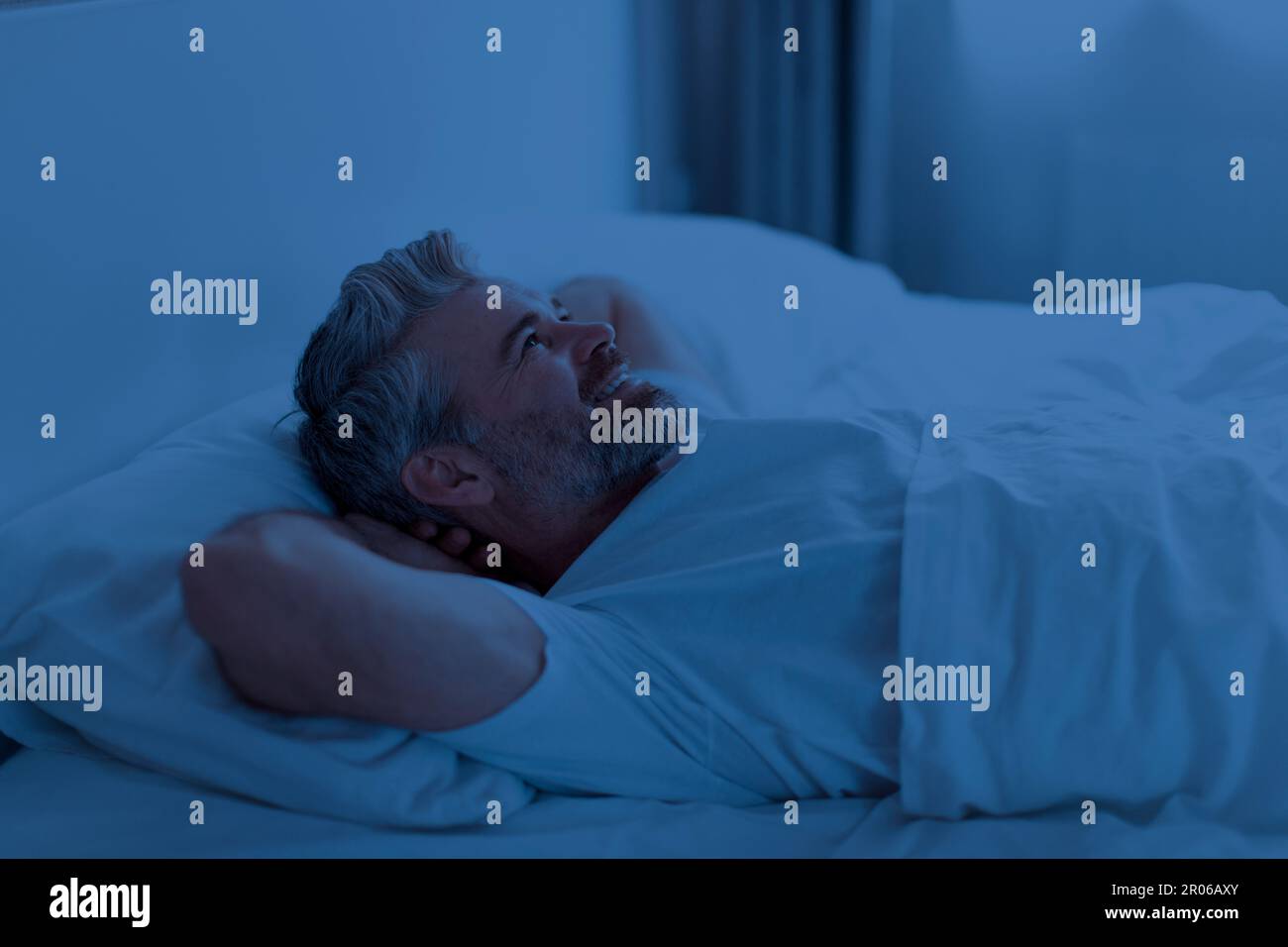 Schlafloser Mann mittleren Alters, der nachts im Bett liegt Stockfoto