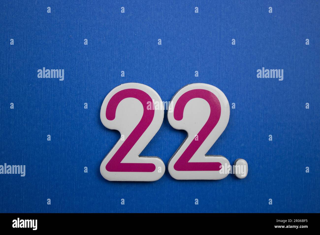 Die Nummer 22, auf blauem Hintergrund, von oben fotografiert, rot und hellblau. Stockfoto