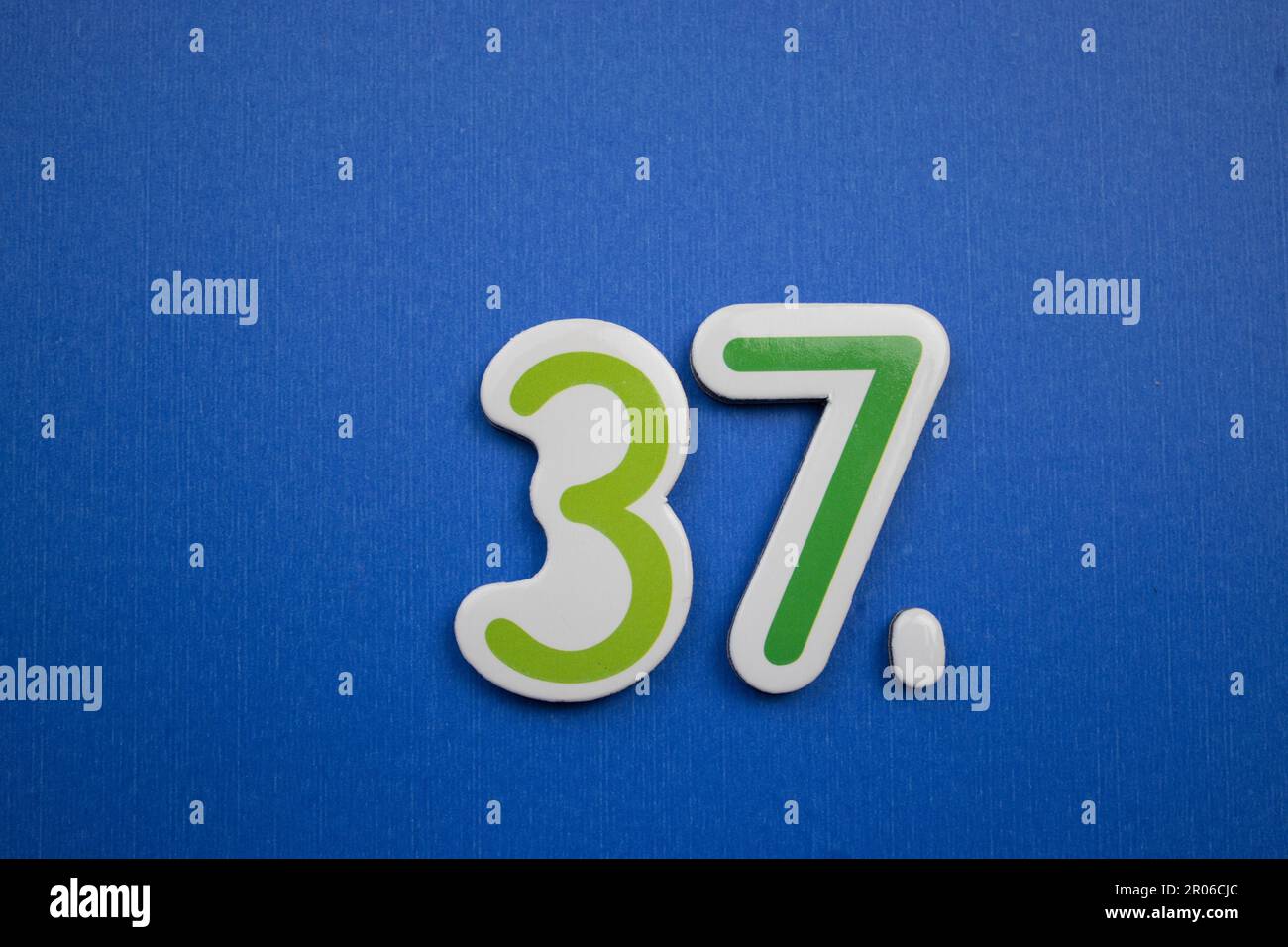 Die Nummer 37, auf blauem Hintergrund, von oben fotografiert, grün und dunkelblau. Stockfoto