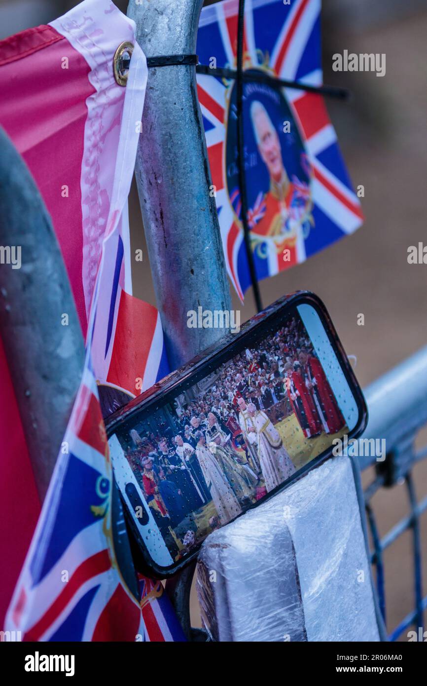 The Mall, London, Großbritannien. 6. Mai 2023 Königliche Fans in der Mall, die die Fernsehsendung der Krönung von König Karl III. Mit einem Handy im Regen sehen. Foto: Amanda Rose/Alamy Live News Stockfoto