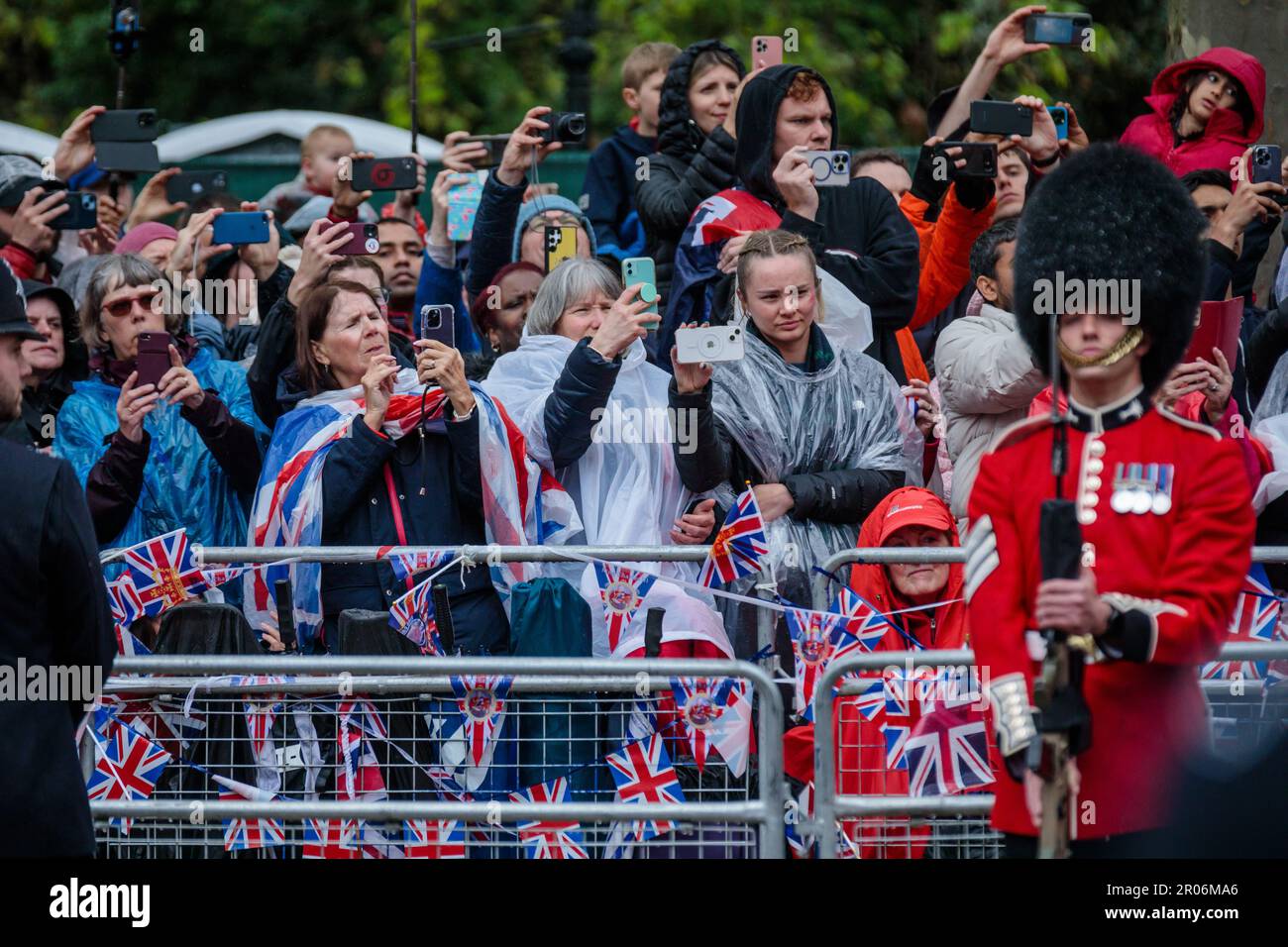 The Mall, London, Großbritannien. 6. Mai 2023 Königliche Fans im Regen auf der Mall während der Prozession zur Krönung von König Karl III. Halten die Action auf ihren Mobiltelefonen fest. Foto: Amanda Rose/Alamy Live News Stockfoto