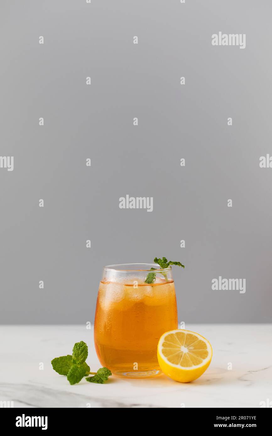 Ein Glas kalten Tee, Eiswürfel, Zitronenscheiben und einen Pfefferminzzweig. Kühle Sommergetränke. Stockfoto