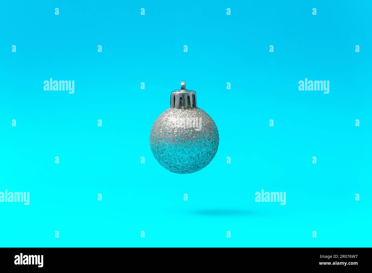 Silbernes Weihnachtsball-Ornament in der Luft auf blauem Hintergrund Stockfoto