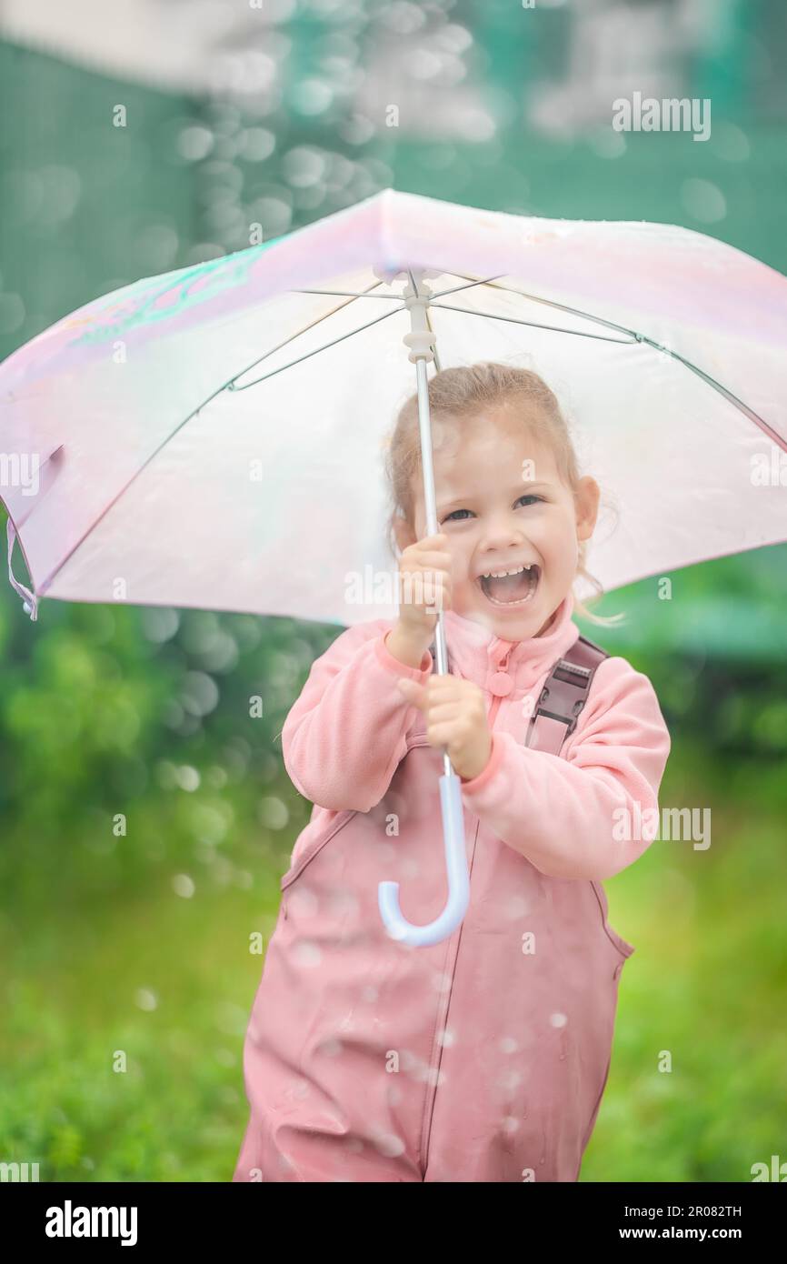 Lächelndes Mädchen in Regenmantel mit Regenschirm in der Hand