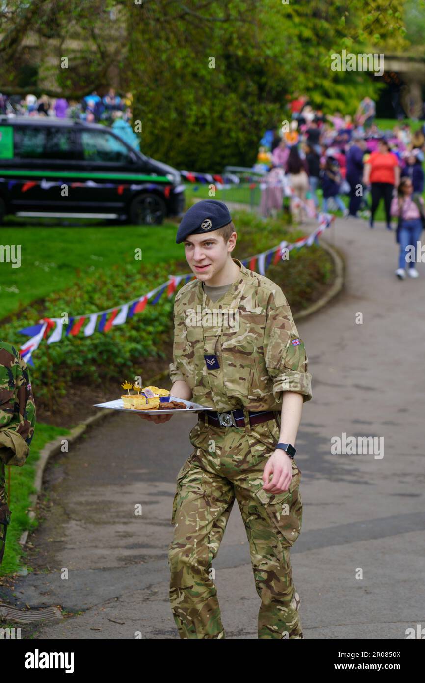 Ein junger männlicher Armeekadett in voller Uniform, der ein Tablett Kuchen bei einer Krönungsfeier von König Karl III. In den Valley Gardens, England, Harrogate, Großbritannien trug. Stockfoto
