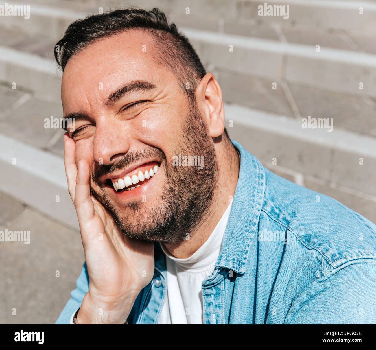 Porträt eines gutaussehenden Hipstermannes in einer jeansjacke in einer Großstadt auf der Straße, ein Lifestyle-Konzept Stockfoto