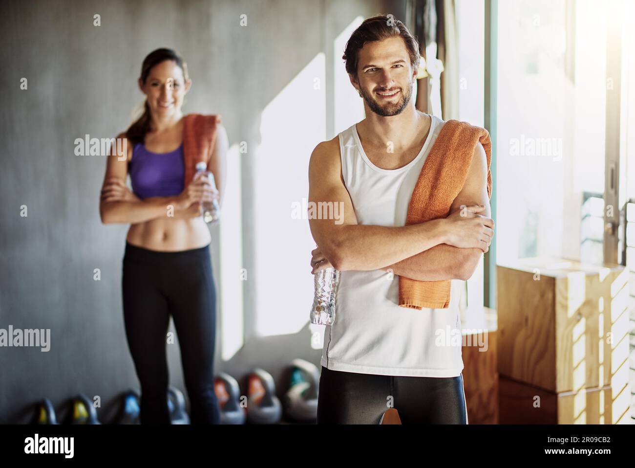 Zusammen fitter zu werden. Zwei junge Leute stehen mit zusammengeklappten Armen im Fitnessstudio. Stockfoto