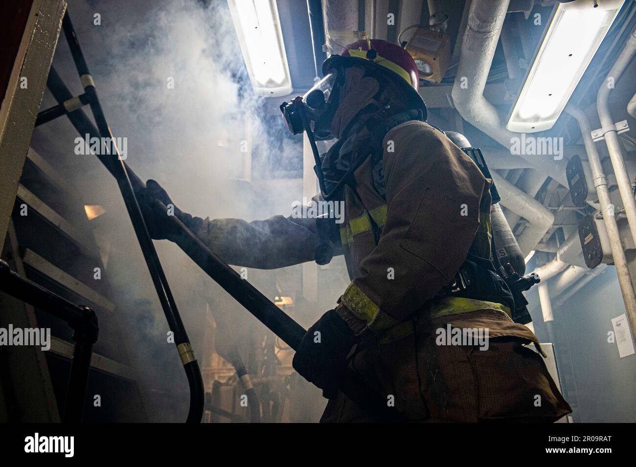 230504-N-NH267-1363 GOLF VON OMAN (4. Mai 2023) Retail Service Specialist Seaman Jeremiah Bridges behält die Kontrolle über einen Feuerwehrschlauch während einer Teamübung zur Schadensbegrenzung in einem Maschinenraum des geführtem Raketenzerstörers USS Paul Hamilton (DDG 60), 4. Mai 2023 im Golf von Oman. Paul Hamilton wird im US-Flottengebiet 5. eingesetzt, um die Sicherheit und Stabilität der Seeschifffahrt im Nahen Osten zu gewährleisten. (USA Marinebild von Mass Communication Specialist 2. Class Elliot Schaudt) Stockfoto