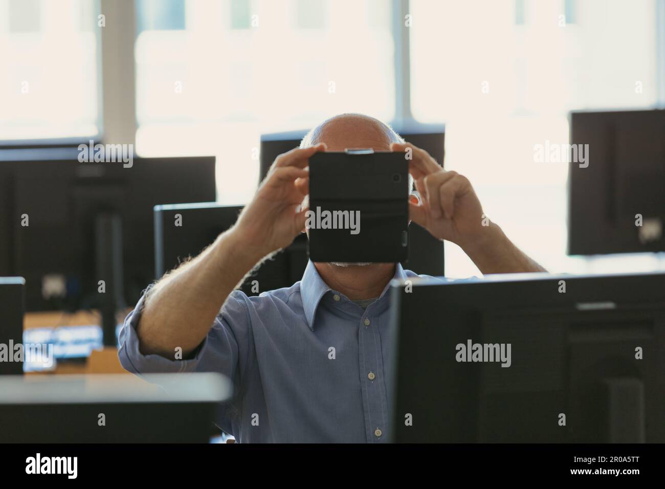 Ein Mann nimmt mit seinem Handy ein Foto oder Video in einem Raum voller Desktop-PCs auf; dies ist ein großes Datenanalysezentrum Stockfoto
