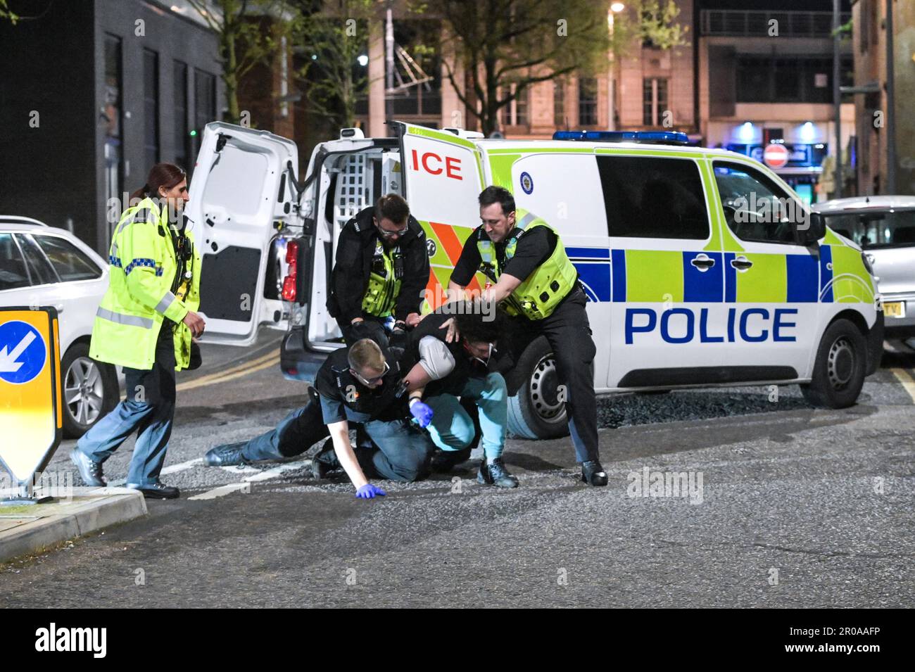 Broad Street, Birmingham, 8. Mai 2023 - die Polizei von West Midlands musste diesen Mann zu Boden ringen, nachdem er sich nach einem Vorfall in einem Nachtclub der Verhaftung widersetzte. Am Sonntagabend stiegen Reveller auf die Broad Street von Birmingham für eine königliche Afterparty ab. Die Polizei war auch bei mehreren anderen Vorfällen entlang des berüchtigten Streifens dabei, als temperiert wurde. Eine Frau wurde von einem Sanitäter in einen Krankenwagen gefahren, der einen Krankenwagen hielt. Die meisten Feiernden trugen normale Wochenend-Outfits, aber einige hielten sich immer noch an den Feierlichkeiten fest, die Union Flag Hüte und König Karl III Masken und große Ohren trugen. Der Partygänger Stockfoto