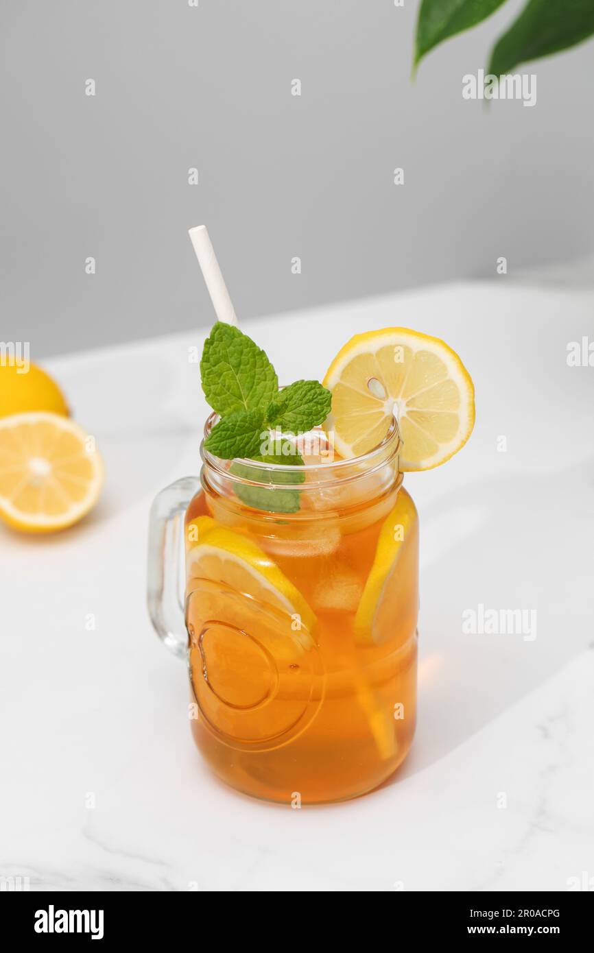 Ein Glas kalten Tee, Eiswürfel, Zitronenscheiben und einen Pfefferminzzweig. Kühle Sommergetränke. Stockfoto