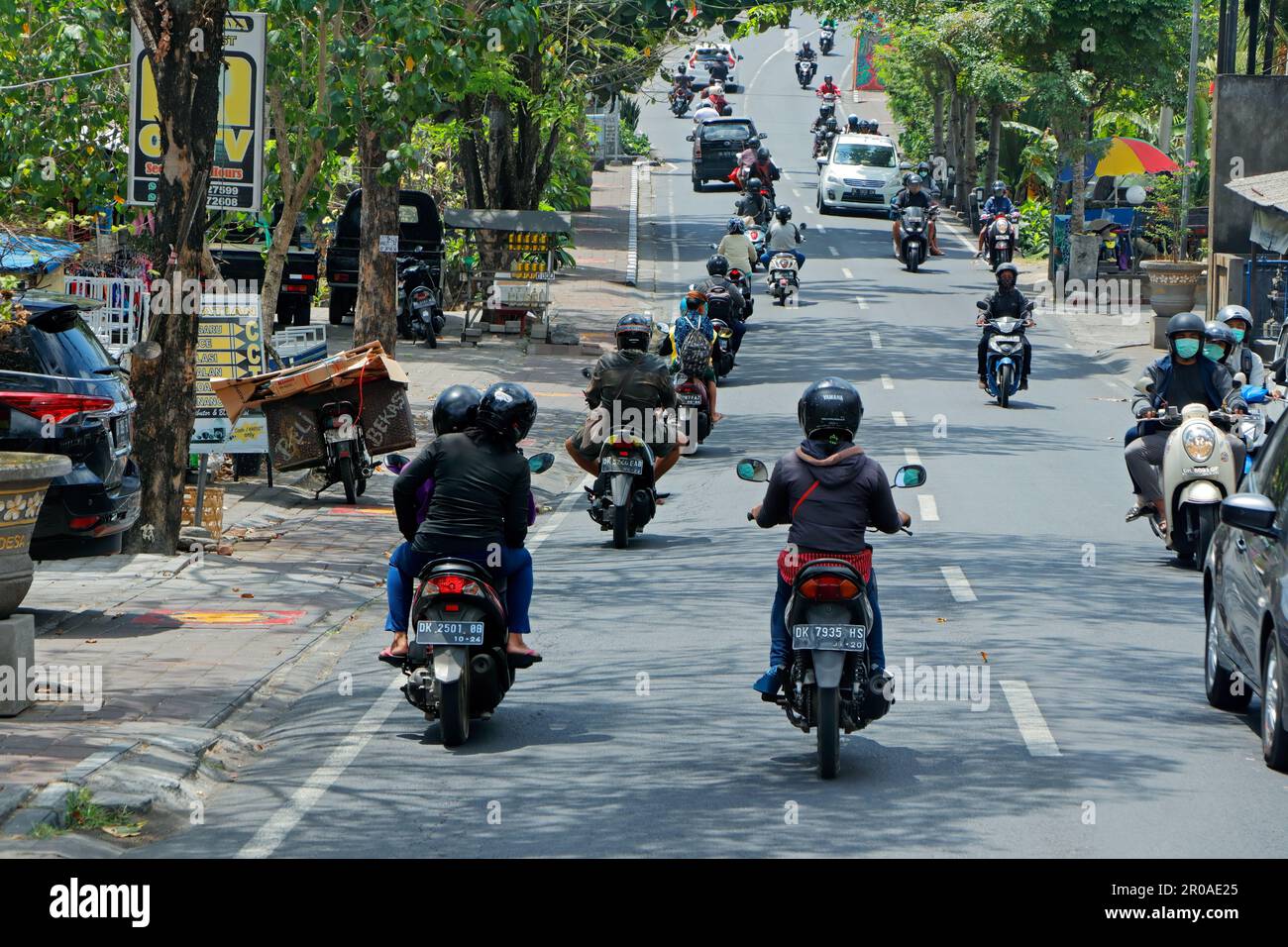 Ubud, Bali, Indonesien - 5. September 2019: Motorräder und Autos fahren in einer belebten Straße mit Straßenläden der beliebten Touristenstadt Stockfoto